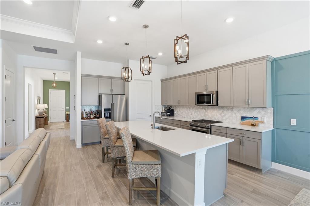 1872 Terreno Boulevard Naples, FL 34120 - Photo 10 of 50 a kitchen with a sink a stove cabinets and wooden floor