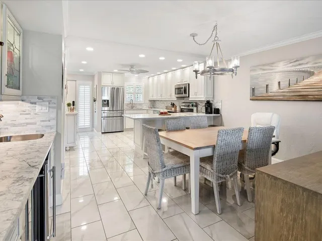 a kitchen with stainless steel appliances kitchen island granite countertop a table and chairs in it