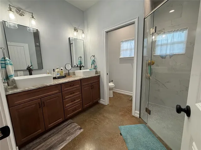 a bathroom with a double vanity sink toilet and shower