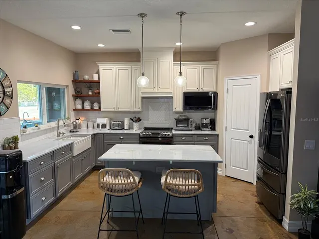 a large kitchen with a large counter top space a sink stainless steel appliances and cabinets