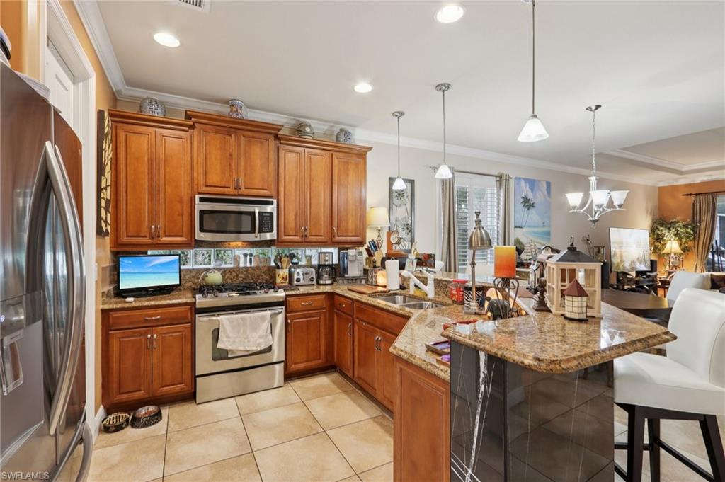 19612 Tesoro Way Estero, FL 33967 - Photo 15 of 50 a kitchen with stainless steel appliances a sink a stove a refrigerator cabinets and chairs