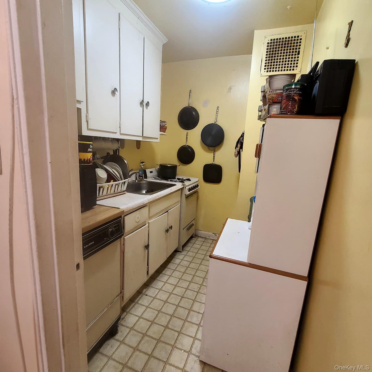83-25 98th Street, Unit 2T Queens, NY 11421 - Photo 3 of 6 a kitchen with a sink a refrigerator and cabinets