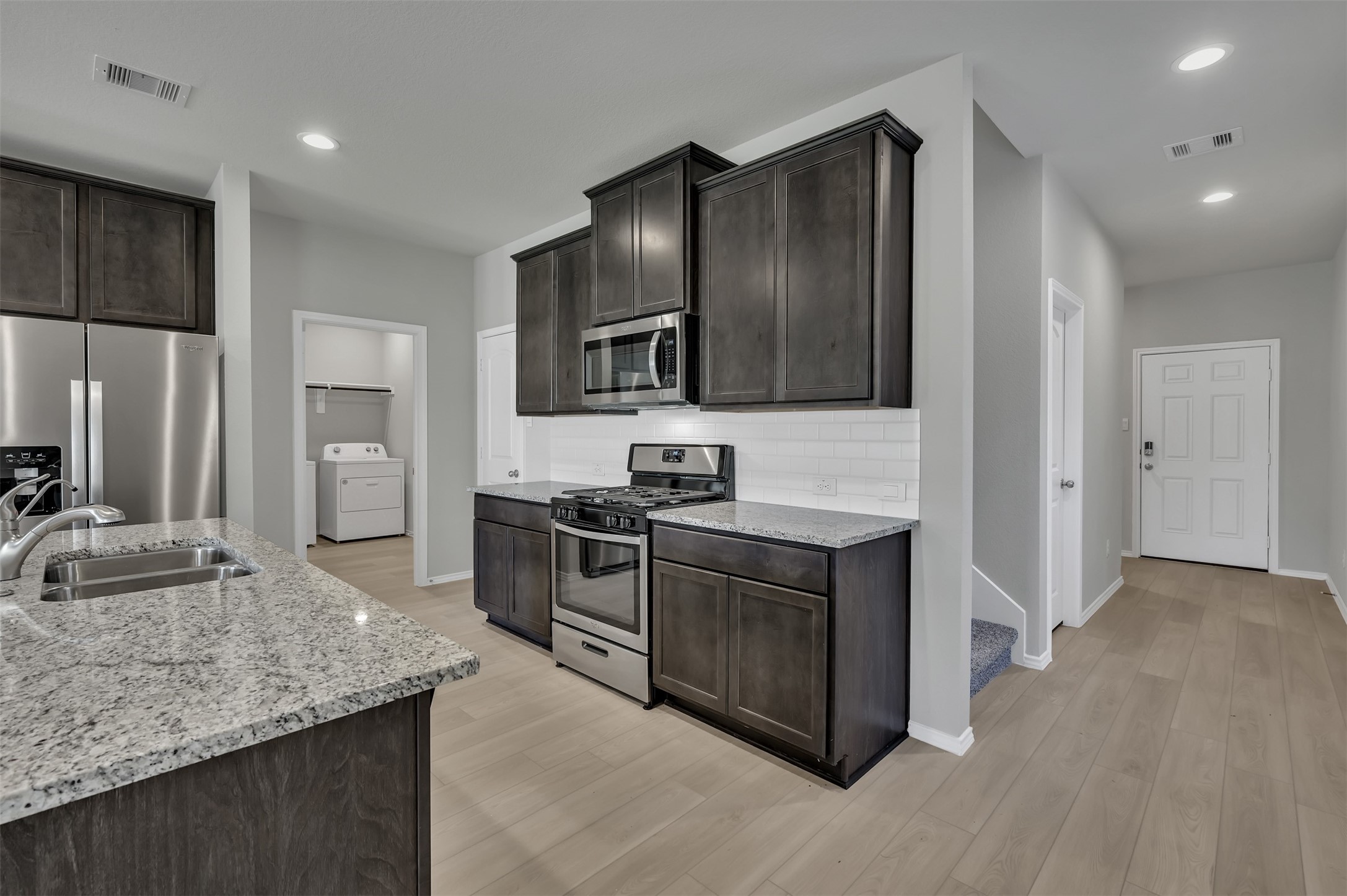 17105 Upland Bent Court Conroe, TX 77385 - Photo 11 of 40 a kitchen with stainless steel appliances granite countertop a stove a sink and a refrigerator with wooden floor