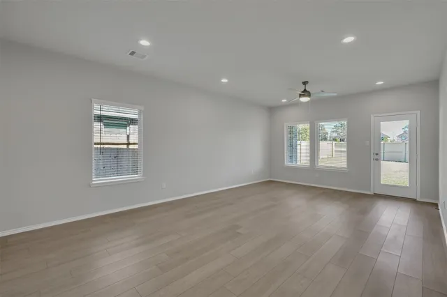 an empty room with wooden floor and windows