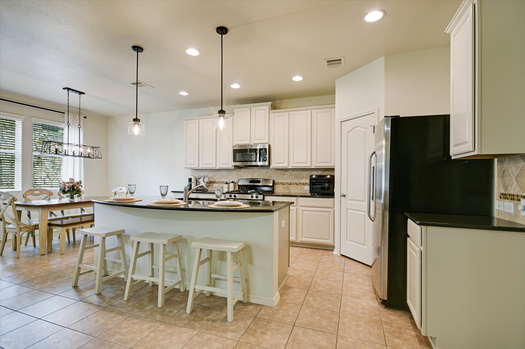 7212 Lookout Bluff Terrace, Unit D18 Austin, TX 78735 - Photo 7 of 22 a kitchen with stainless steel appliances granite countertop a refrigerator a stove a sink a dining table and chairs
