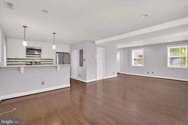 a view of an empty room with wooden floor and a window