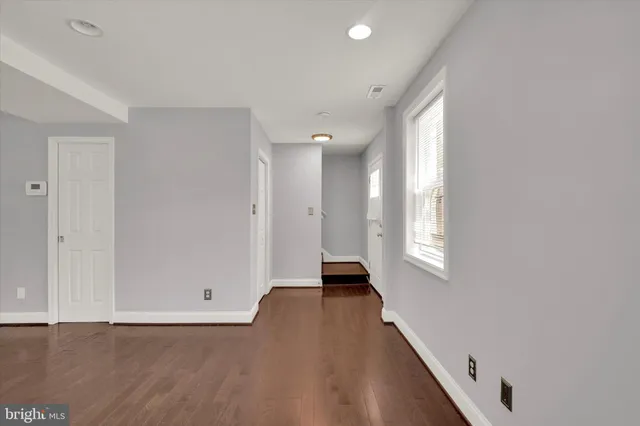 a view of kitchen with stainless steel appliances granite countertop a refrigerator a sink dishwasher a stove and white cabinets with wooden floor