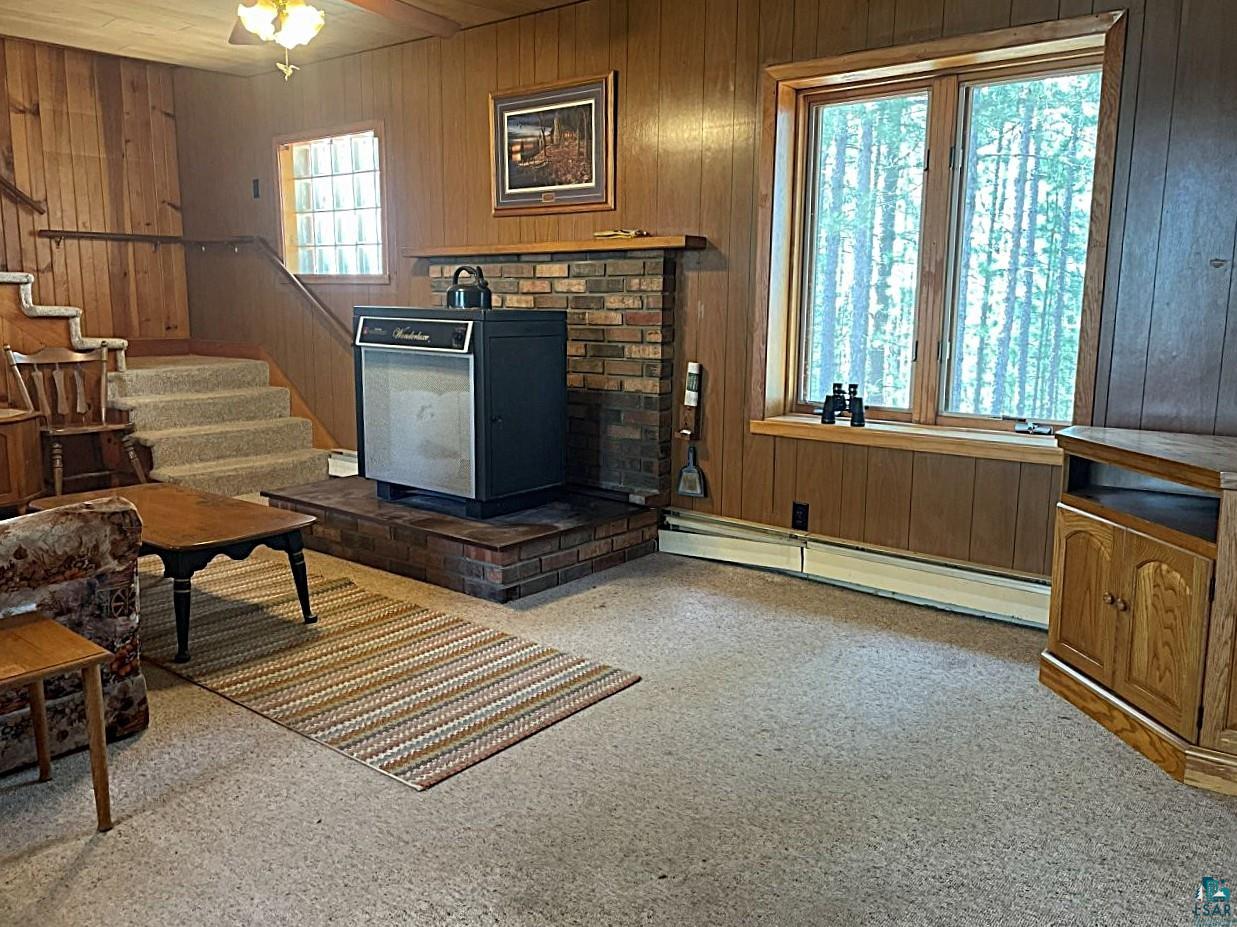 1480 Maijala Road Ely, MN 55731 - Photo 19 of 58 Spacious living area featuring wood paneling, a raised brick hearth for wood fireplace, and a large window