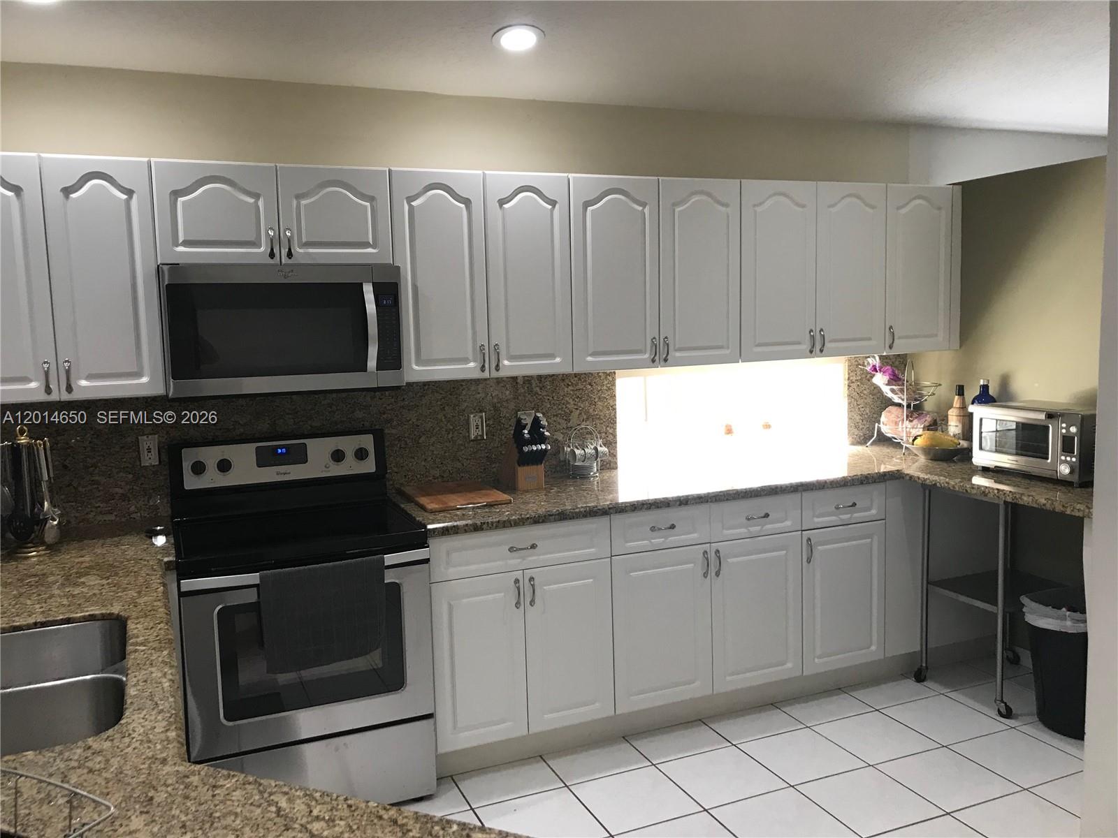 16654 Southwest 103rd Lane Miami, FL 33196 - Photo 4 of 20 a kitchen with granite countertop white cabinets and stainless steel appliances