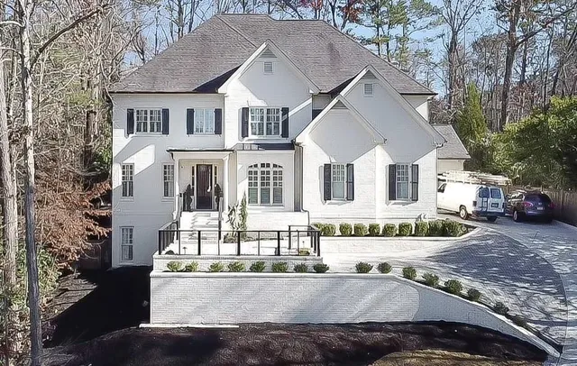 a view of a white house with large windows and a tree