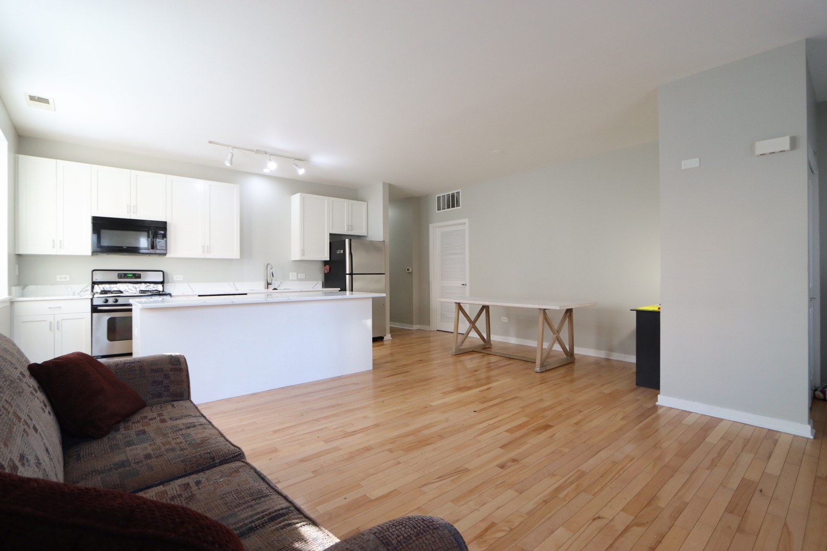 914 South Racine Avenue, Unit 101 Chicago, IL 60607 - Photo 5 of 17 a open kitchen with kitchen island a sink dishwasher a stove and a refrigerator with wooden floor