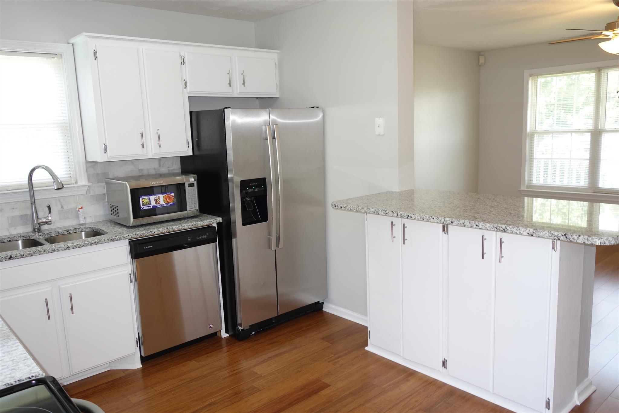 1545 Ridgemont Drive La Vergne, TN 37086 - Photo 9 of 25 a kitchen with granite countertop a refrigerator a sink a stove and white cabinets with wooden floor