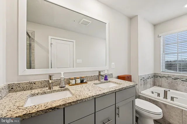 a bathroom with a granite countertop sink a toilet and bathtub