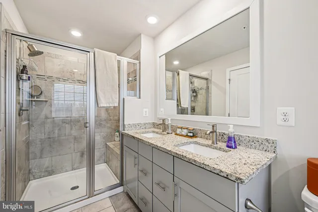 a bathroom with a shower sink vanity granite and mirror