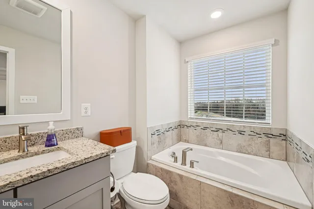 a bathroom with a granite countertop sink toilet and bathtub