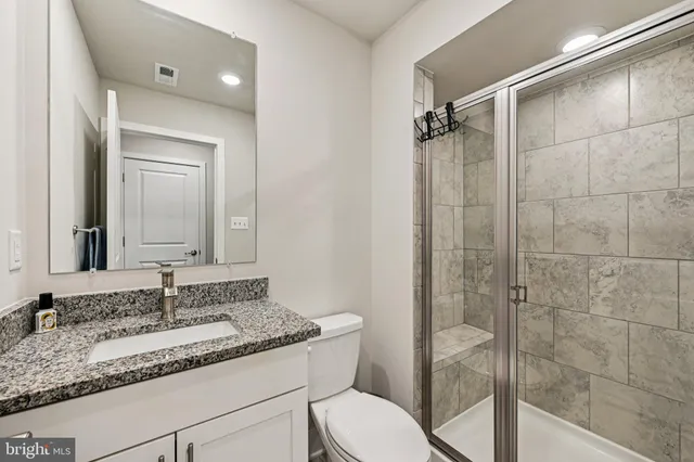 a bathroom with a granite countertop sink toilet and shower