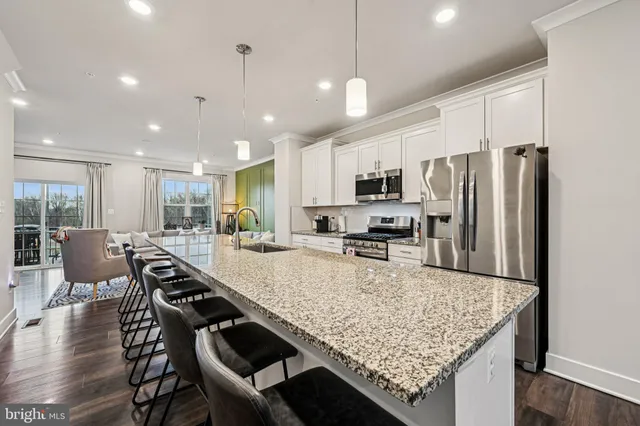 a kitchen with stainless steel appliances granite countertop a stove top oven a refrigerator a sink and chairs