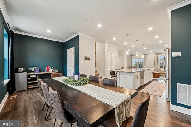 a dining hall with stainless steel appliances kitchen island granite countertop a dining table chairs and view of living room