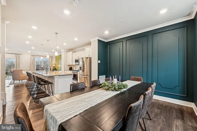 a dining room with furniture a kitchen view and wooden floor