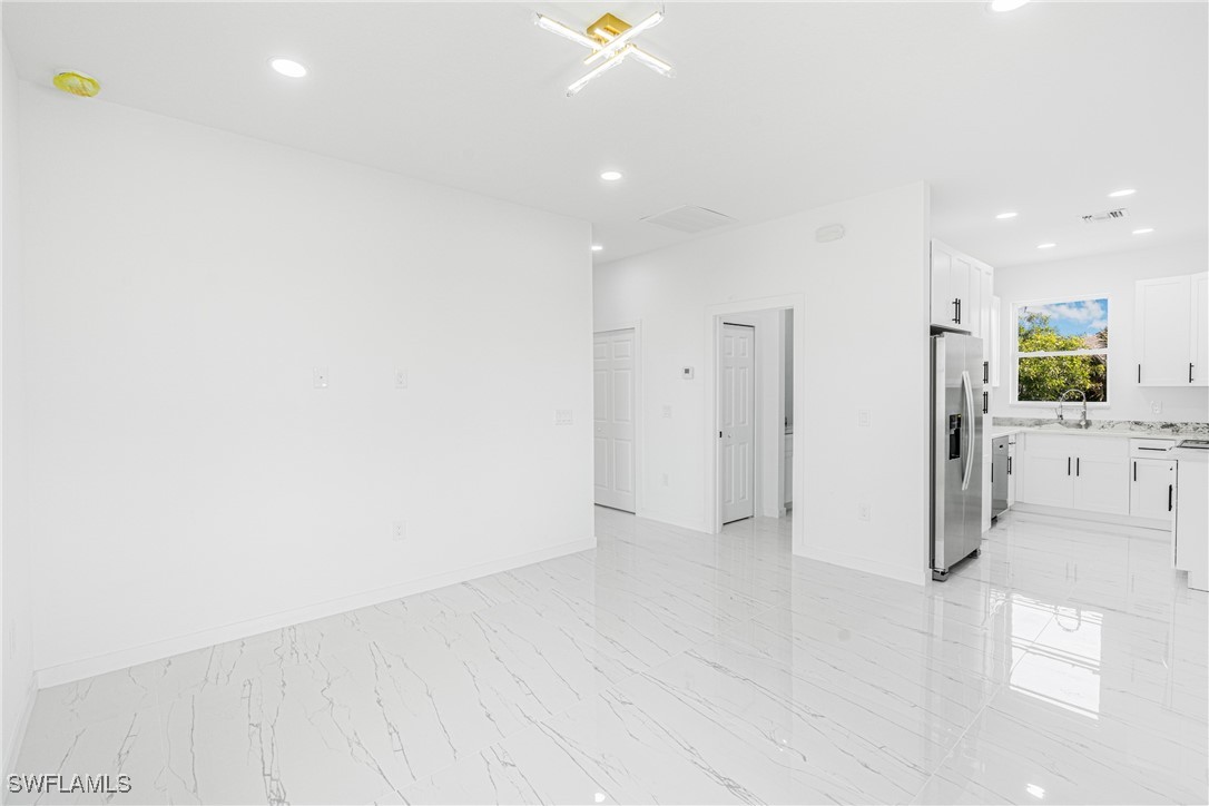3604 26th Street Southwest Lehigh Acres, FL 33976 - Photo 14 of 38 wooden floor in an empty room with a kitchen