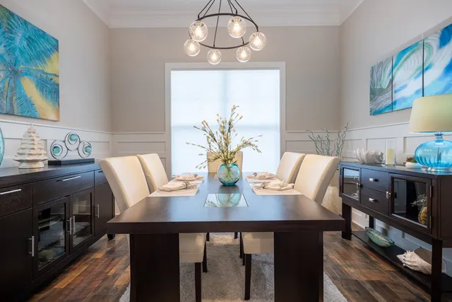 a kitchen with stainless steel appliances granite countertop a refrigerator a stove a kitchen island a dining table and chairs with wooden floor