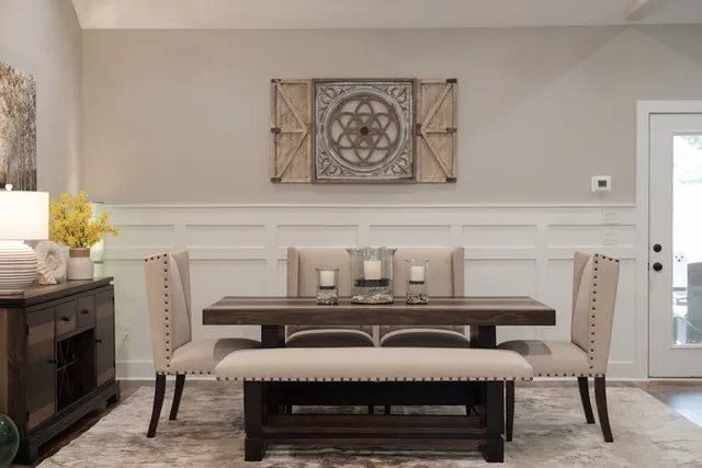 a kitchen with stainless steel appliances granite countertop a refrigerator a stove top oven a dining table and chairs with wooden floor