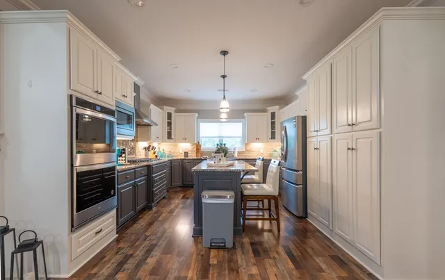 a kitchen with stainless steel appliances granite countertop a lot of counter space and wooden floors