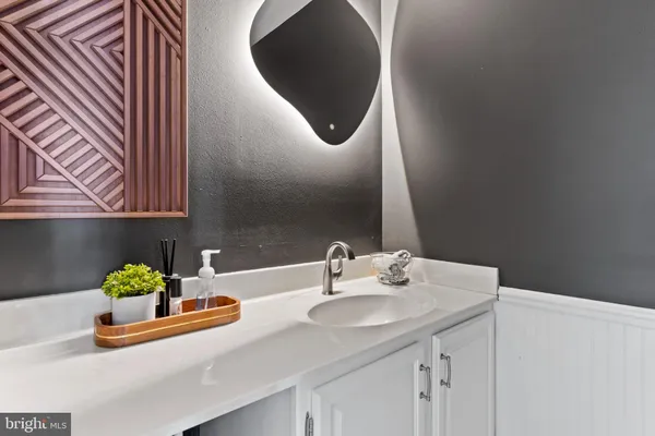 a bathroom with a sink a mirror and a potted plant