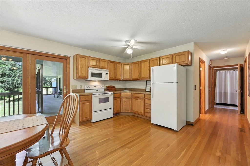 285 Lower Hampden Road Monson, MA 01057 - Photo 22 of 40 a kitchen with a refrigerator a stove top oven a sink dishwasher and a dining table with wooden floor