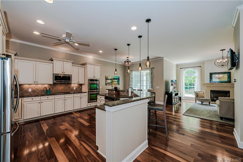 651 Quicksilver Trail Fort Mill, SC 29708 - Photo 7 of 37 a kitchen with stainless steel appliances kitchen island granite countertop a stove top oven a sink a dining table and chairs with wooden floor