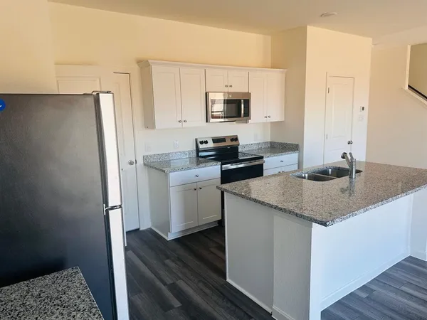 a kitchen with stainless steel appliances granite countertop a sink stove and refrigerator