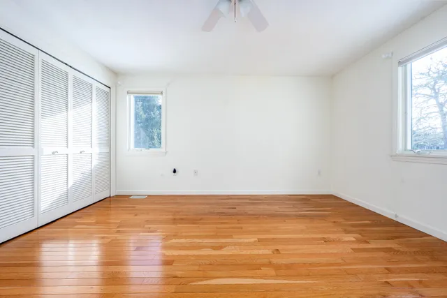 an empty room with wooden floor and windows