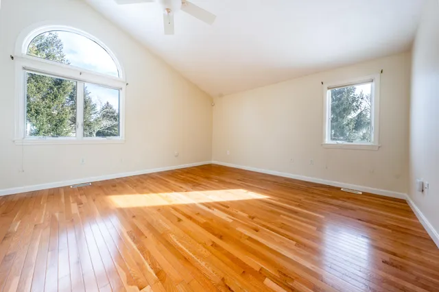 a view of empty room with wooden floor and fan