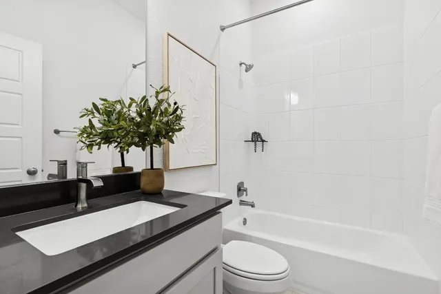 a bathroom with a granite countertop sink a toilet a mirror and shower