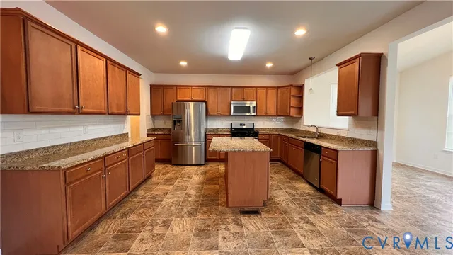 a large kitchen with stainless steel appliances granite countertop a stove top oven a sink dishwasher a dining table and chairs with wooden floor