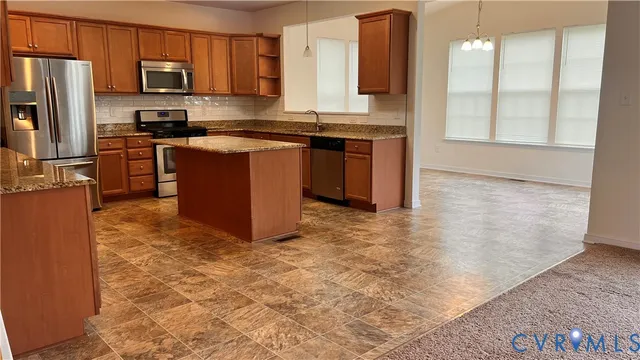 a kitchen with stainless steel appliances granite countertop a stove top oven a sink and a refrigerator