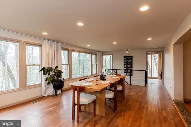 a very nice looking open dining room with kitchen island furniture a refrigerator a stove a sink and a large window
