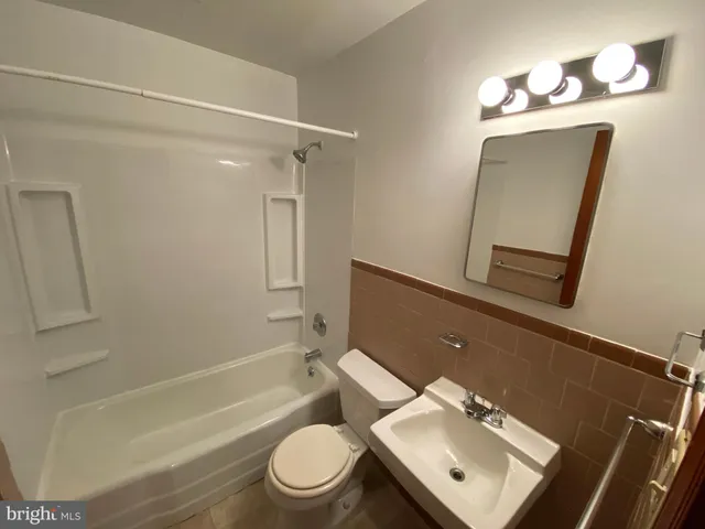 a bathroom with a toilet sink vanity tub and mirror