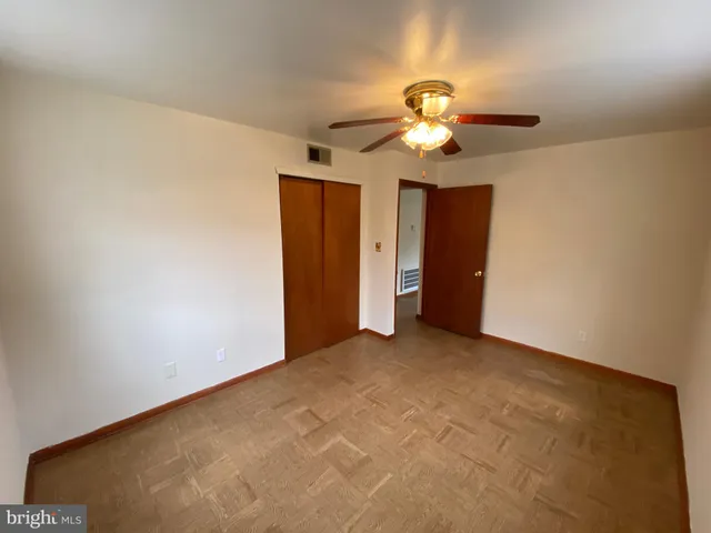 an empty room with closet and a chandelier fan