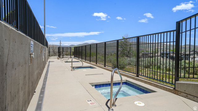 1364 Still Water Drive, Unit R2012 Heber City, UT 84032 - Photo 28 of 30 Outdoor amenity area featuring multiple hot tubs with blue tile interiors, concrete decking, and metal railings