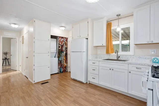 a kitchen with white cabinets and wooden floor