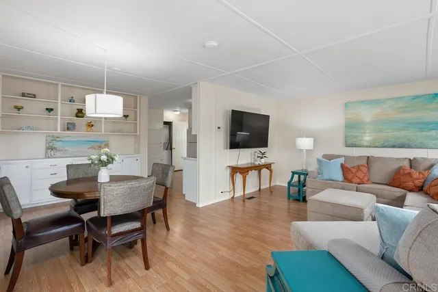 a living room with furniture a flat screen tv and kitchen view