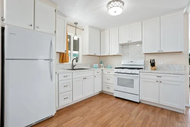 a kitchen with granite countertop white cabinets and white appliances