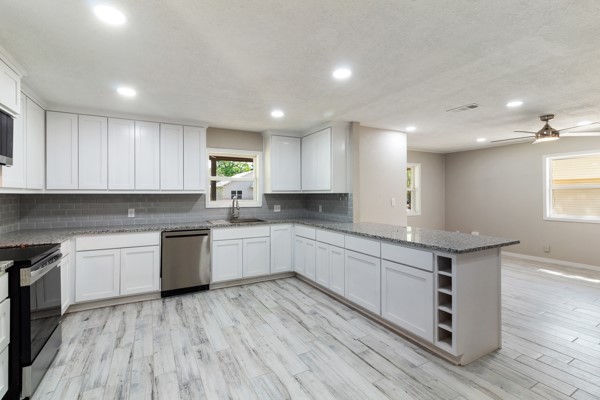4104 Marsh Street Bryan, TX 77803 - Photo 7 of 26 a kitchen with granite countertop white cabinets a sink and dishwasher a stove with wooden floors