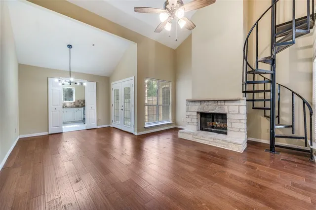 a view of a livingroom with wooden floor a ceiling fan and staircase