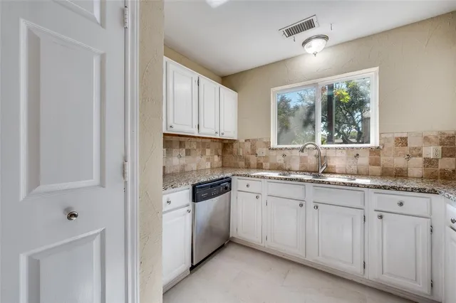 a kitchen with granite countertop white cabinets white appliances a sink and a window