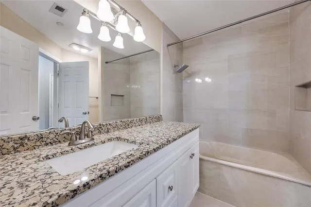 a bathroom with a granite countertop sink a mirror and a bathtub