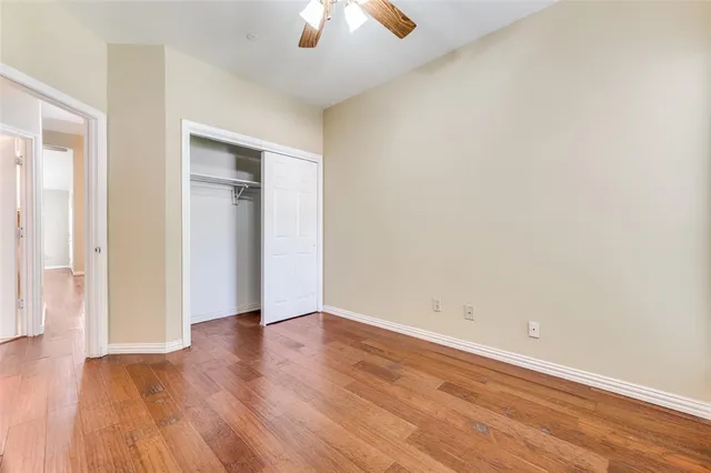 an empty room with wooden floor and chandelier fan