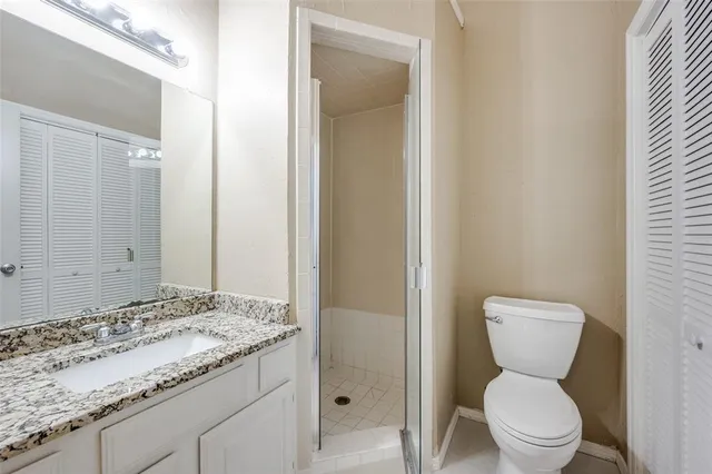a bathroom with a granite countertop toilet and a sink
