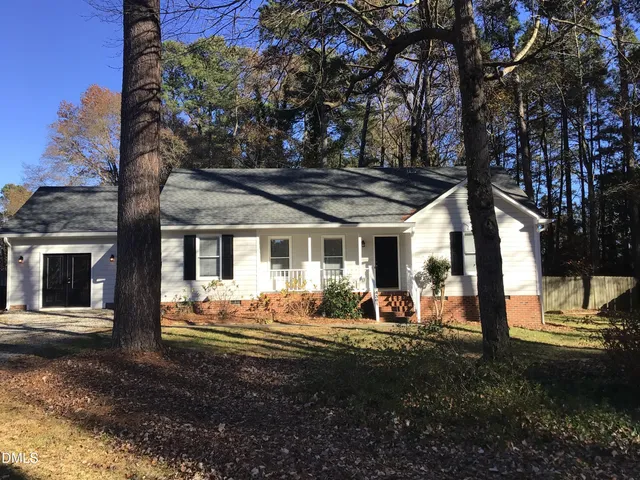a view of a house with backyard outdoor seating and covered with trees